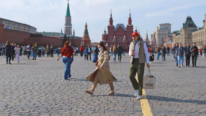 Moscow, Russia: Walking tourists on Red Square Crowd of tourists Young woman wearing face mask